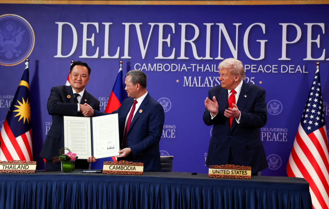 Presiden AS Donald Trump menyaksikan PM Thailand Anutin Charnvirakul dan PM Kamboja Hun Manet menunjukkan dokumen penandatanganan kesepakatan gencatan senjata di sela-sela KTT ke-47 ASEAN di Kuala Lumpur, Malaysia, Minggu (26/10/2025). Foto: Evelyn Hockstein/REUTERS