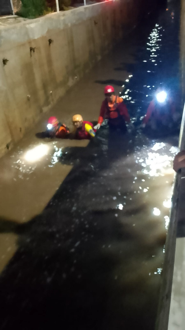 Upaya pencarian bocah 8 tahun yang hanyut ke kali saat bermain hujan di Pamulang Estate, Tangsel pada Minggu (26/10/2025) malam. Foto: Dok. BPBD Tangsel