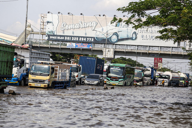 Sejumlah kendaraan berjalan perlahan saat berusaha menembus banjir yang masih menggenangi jalur utama pantura Semarang-Demak di Jalan Kaligawe Raya, Semarang, Jawa Tengah, Senin (27/10/2025). Foto: Makna Zaezar/ANTARA FOTO