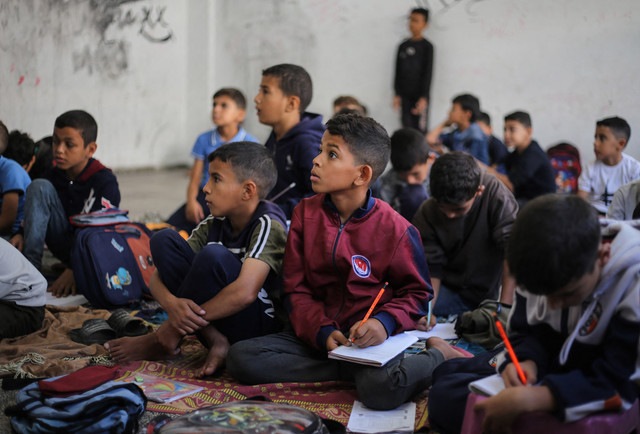 Anak-anak sekolah Palestina mendengarkan guru mereka di sebuah sekolah di kamp pengungsi Nuseirat, di Jalur Gaza tengah, Minggu (26/10/2025). Foto: EYAD BABA/AFP