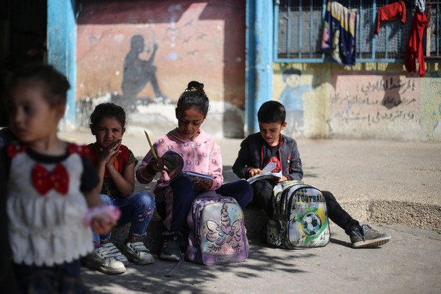 Anak-anak Palestina duduk dengan buku-buku sekolah mereka di sebuah sekolah di kamp pengungsi Nuseirat, di Jalur Gaza tengah, Minggu (26/10/2025). Foto: EYAD BABA/AFP