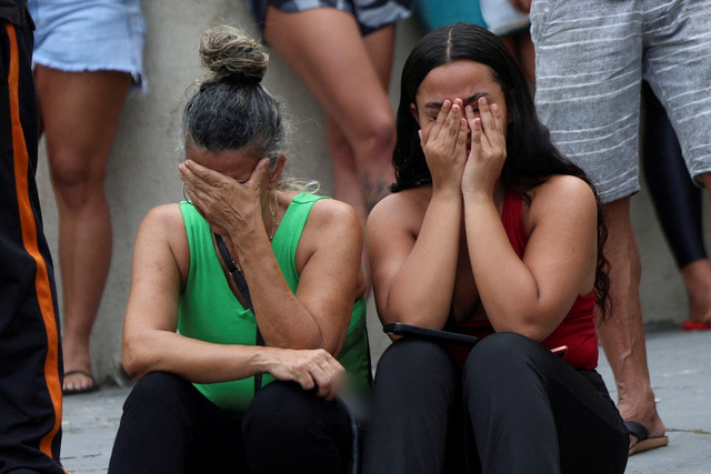 Dua wanita menangis saat menunggu kabar di luar rumah sakit pada hari operasi polisi melawan perdagangan narkoba di favela do Penha, Rio de Janeiro, Brasil, Selasa (28/10/2025). Foto: Aline Massuca/REUTERS