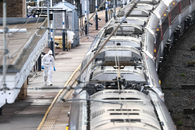 Seorang petugas forensik bekerja di dekat kereta London North Eastern Railway tempat serangkaian penusukan terjadi, di peron Stasiun Huntingdon, dekat Cambridge, Inggris, Minggu (2/11/2025). Foto: Jack Taylor/REUTERS 