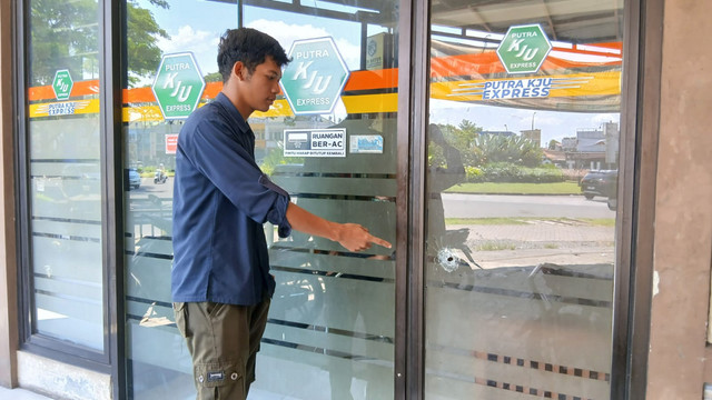 Warga menunjukkan lubang bekas peluru di kantor pengiriman barang di kawasan Citra Raya. Foto: kumparan