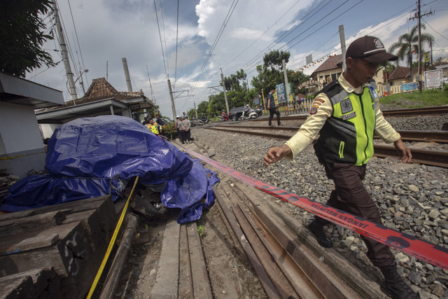 Petugas memasang police line di dekat mobil yang tertabrak kereta 161 Bangunkarta di perlintasan antara Stasiun Brambanan dan Maguwo, Prambanan, Sleman, D.I Yogyakarta, Selasa (4/11/2025). Foto: Andreas Fitri Atmoko/ANTARA FOTO