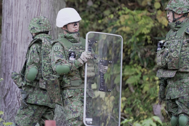 Seorang anggota Pasukan Bela Diri Jepang (JSDF) memegang perisai saat berlatih memasang perangkap beruang di Kazuno, Prefektur Akita, Jepang, Rabu (5/11/2025). Foto: Tom Bateman/REUTERS