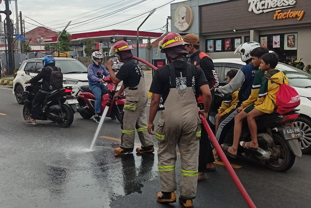 Petugas Damkar membersihkan tumpahan oli berceceran di jalan raya Sawangan, Depok, Kamis (6/11/2025). Foto: Damkar Depok