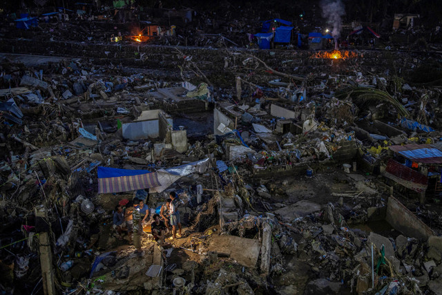 Warga menggunakan senter untuk mencari jalan keluar dari permukiman mereka yang rumahnya tersapu banjir akibat Topan Kalmaegi di Talisay, Cebu, Filipina, 6 November 2025. Foto: REUTERS/Eloisa Lopez