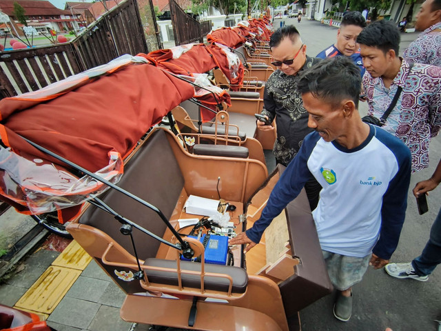 Salah satu penerima bantuan becak listrik saat menunjukkan baterai becak listriknya, Kamis (13/11/2025). Foto: kumparan