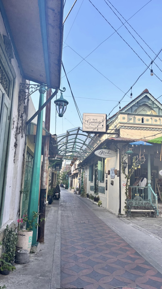 An original photo of a street in Kampung Batik Kauman, showing both a batik production site and a café that attracts visitors, was documented by Gregorius Alessandro Bria Nahak, the writer himself.