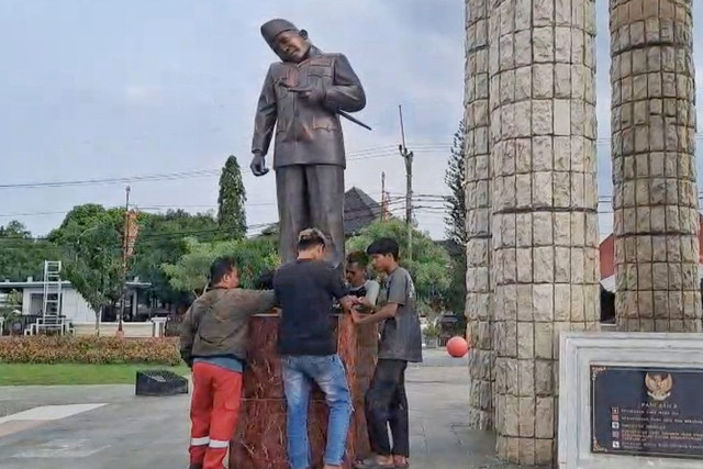 Petugas menurunkan patung Soekarno yang kepalanya terlihat miring, di Alun-alun Kabupaten Indramayu. Foto: Ist