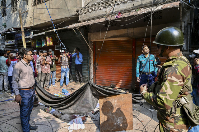 Seorang anggota militer berjaga di dekat puing-puing yang jatuh dari bangunan yang rusak akibat gempa bumi di Old Dhaka, Jumat (21/11/2025). Foto: Munir Uz zaman/AFP