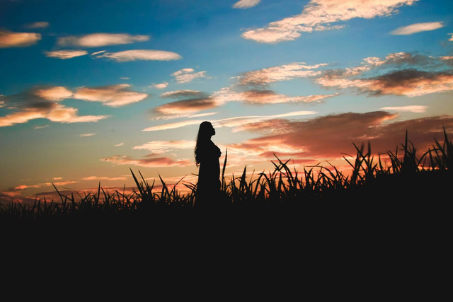 Foto oleh Doci, Pexels. Seseorang berdiri memandang matahari terbenam—sebuah momen refleksi tentang perjalanan hidup yang berjalan pelan namun