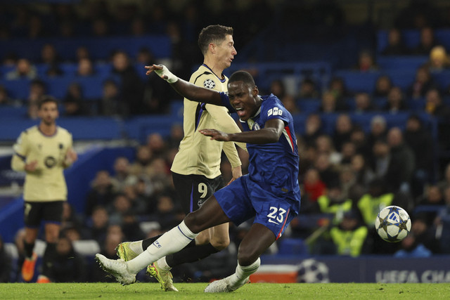 Pemain Chelsea Trevoh Chalobah terjatuh saat berebut bola dengan pemain FC Barcelona Robert Lewandowski dalam pertandingan fase liga Liga Champions di Stamford Bridge, London, Inggris, Selasa (25/11/2025). Foto: Adrian Dennis/AFP