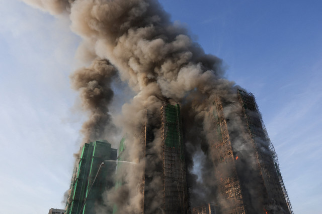 Asap mengepul saat api melahap perancah bambu di beberapa gedung di perumahan Wang Fuk Court, Tai Po, Hong Kong, Rabu (26/11/2025). Foto: Tyrone Siu/REUTERS