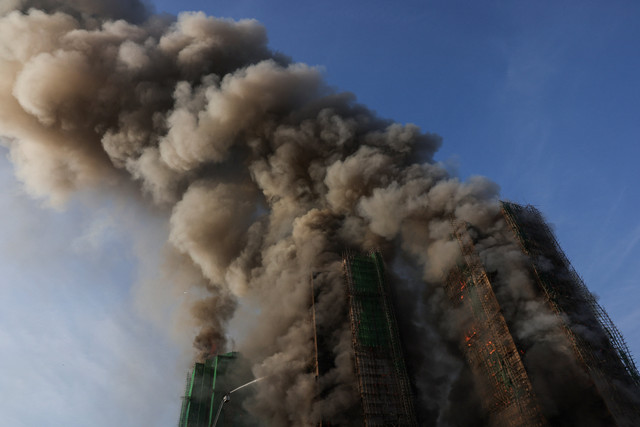 Asap mengepul saat api melahap perancah bambu di beberapa gedung di perumahan Wang Fuk Court, Tai Po, Hong Kong, Rabu (26/11/2025). Foto: Tyrone Siu/REUTERS