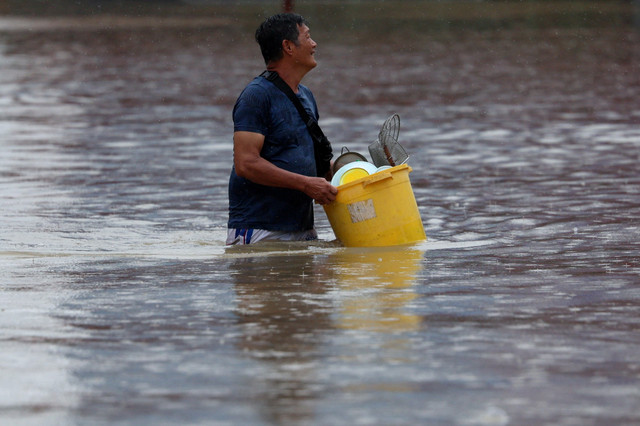 Warga berjalan melewati banjir yang merendam di Kangar, Malaysia, Rabu (26/11/2025). Foto: Hasnoor Hussain/REUTERS