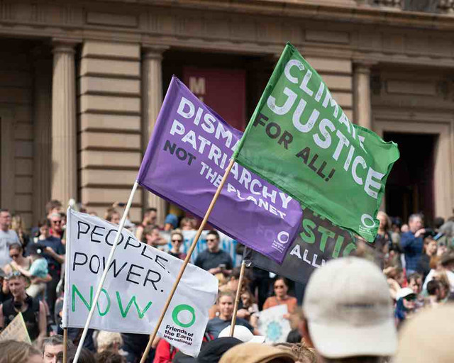 Sekelompok orang membawa bendera climate justice untut menuntut keadilan iklim. Foto: unsplash.com