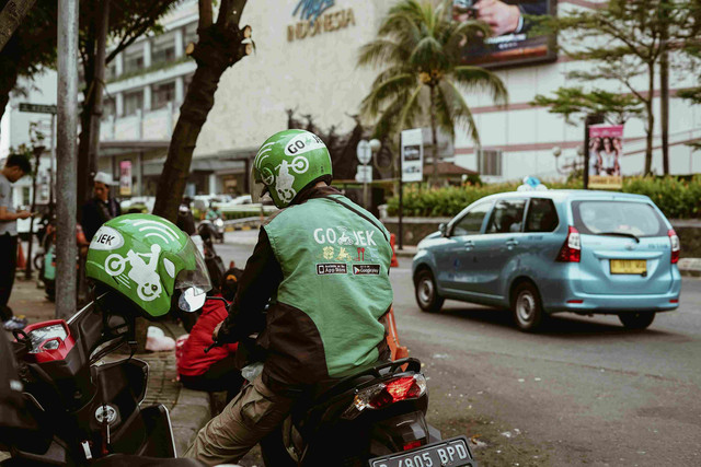 Ojek online sedang memperhatikan aplikasinya (unsplash/Afif Ramdhakusuma)