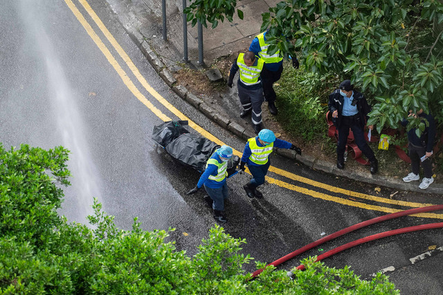 Para pekerja mengevakuasi jenazah dari kebakaran yang terjadi Rabu di Wang Fuk Court, sebuah kompleks perumahan di distrik Tai Po, Wilayah Baru Hong Kong, Kamis (27/11/2025). Foto: Chan Long Hei/AP Photo