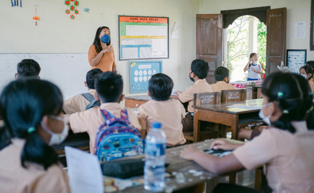 Suasana pembelajaran di sebuah kelas sekolah dasar, ketika guru menyampaikan materi kepada para siswa. Foto oleh Agung Pandit Wiguna dari Pexels: https://www.pexels.com/id-id/foto/wanita-perempuan-kaum-wanita-sekolah-12125962/