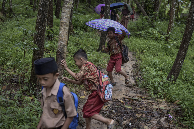 Siswa terpeleset saat berjalan melintasi hutan untuk pulang. Foto: Muhammad Bagus Khoirunas/ANTARA FOTO