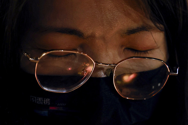 Sejumlah warga berdoa dengan membawa lilin saat aksi mengenang kematian ratusan orang dalam kebakaran Apartemen di Tai Po, Hong Kong, Jumat (28/11/2025). Foto: Maxim Shemetov/REUTERS