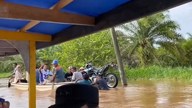 Warga menggunakan perahu melewati banjir di Desa Singkuang, Kecamatan Muara Batang Gadis, Senin (1/12/2025). Foto: Instagram/@polresmandailingnatal
