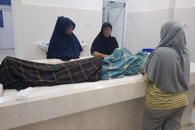 Keluarga berdiri disamping jenazah Muhammad (73), warga yang meninggal dunia setelah diduga mengalami serangan jantung saat kepanikan massal akibat hoaks tsunami di Pidie Jaya, Senin (1/12/2025). Foto: Istimewa