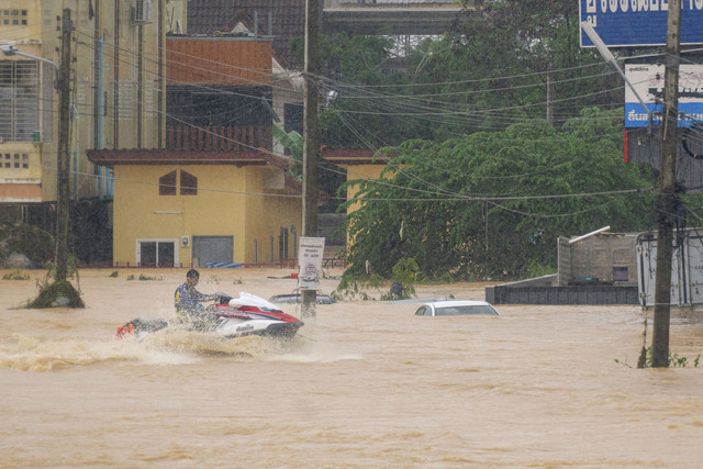 Seorang pria mengendarai jet ski melintasi air banjir di Hat Yai, Provinsi Songkhla bagian selatan Thailand, Rabu (26/11/2025). Foto: Arnun Chonmahatrakool / THAI NEWS PIX / AFP