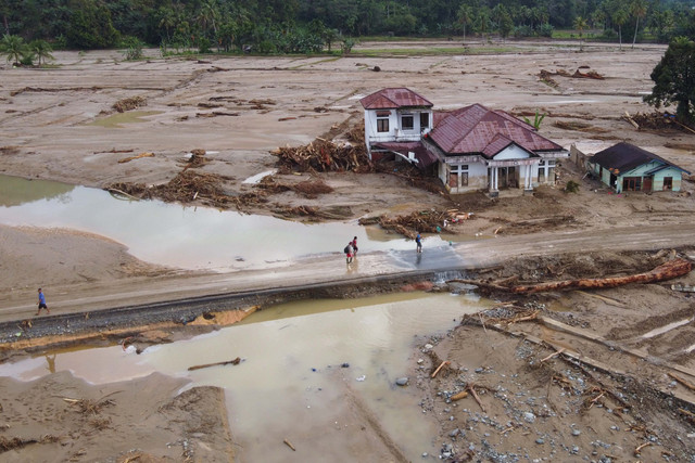 Foto udara menunjukkan warga berjalan di jalan berlumpur di sebuah desa yang terdampak banjir bandang di Batang Toru, Sumatera Utara, Selasa (2/12/2025). Foto: Binsar Bakkara/AP Photo