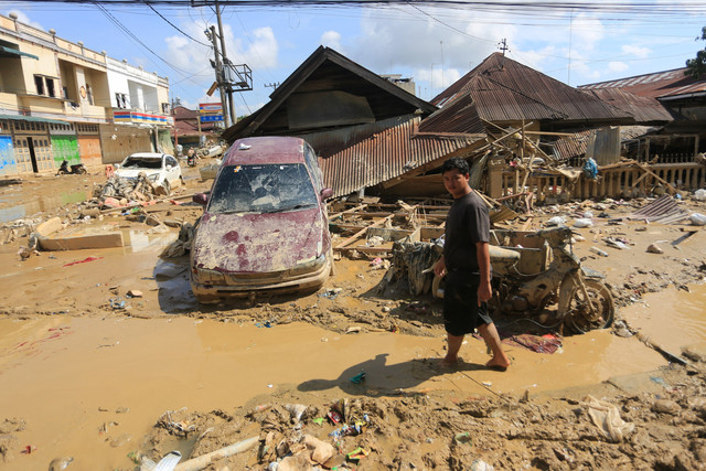 Warga melintas di dekat mobil warga yang terbawa arus banjir di kawasan Desa Bukit Tempurung, Kota Kuala Simpang, Kabupaten Aceh Tamiang, Aceh, Rabu  (3/12/2025). Foto: Syifa Yulinnas/ANTARA FOTO