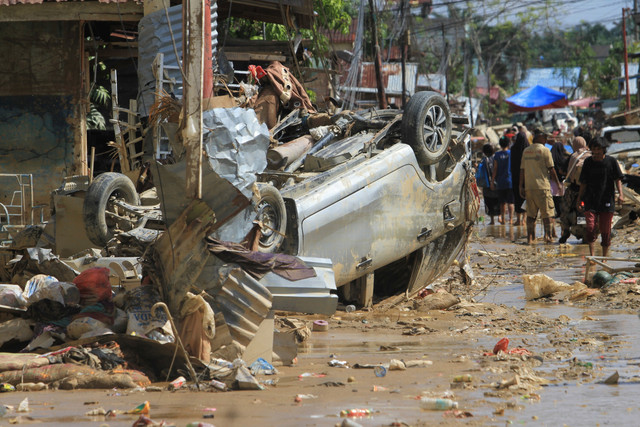 Sejumlah warga melintas di dekat mobil warga yang terbawa arus banjir di kawasan Desa Bukit Tempurung, Kota Kuala Simpang, Kabupaten Aceh Tamiang, Aceh, Rabu (3/12/2025). Foto: Syifa Yulinnas/ANTARA FOTO