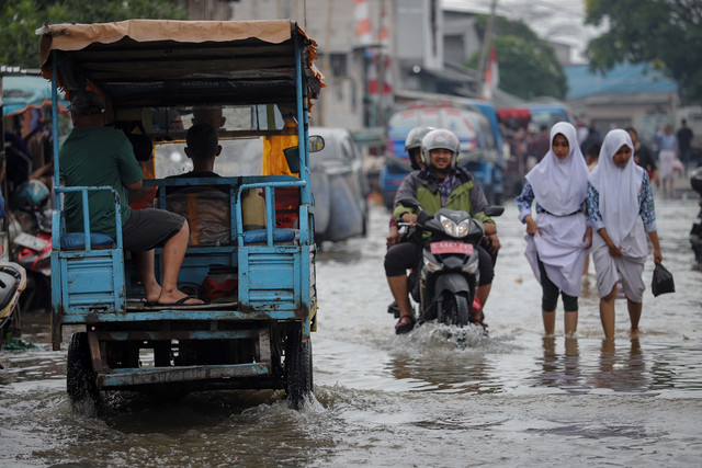 Sejumlah warga melintasi genangan air akibat banjir rob yang melanda kawasan Muara Angke, Jakarta Utara, Kamis (4/12/2025). Foto: Jamal Ramadhan/kumparan
