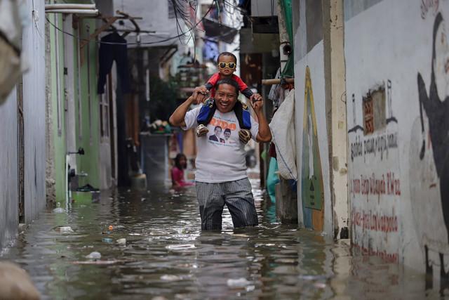 Sejumlah warga melintasi genangan air akibat banjir rob yang melanda kawasan Muara Angke, Jakarta Utara, Kamis (4/12/2025). Foto: Jamal Ramadhan/kumparan