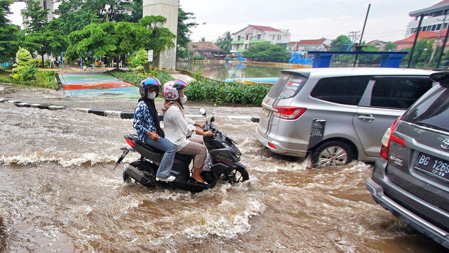 Pengendara motor yang menerobos banjir saat genangan air terjadi akibat hujan deras melanda Kota Palembang sejak pagi, Minggu (7/4/2024) Foto: ary priyanto/urban id