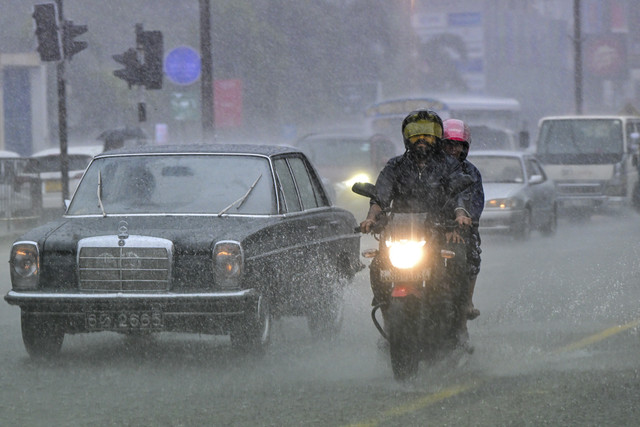 Pengendara sepeda motor melintasi jalan yang tergenang oleh air saat hujan di Colombo, Sri Lanka, Jumat (5/12/2025). Foto: Ishara S. Kodikara/AFP