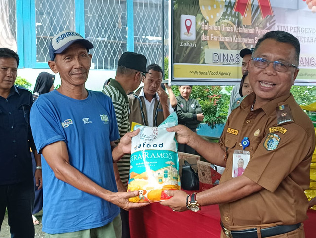 Plt Kepala Dinas Ketahanan Pangan dan Perikanan Kabupaten Sintang, Helmi menyerahkan beras secara simbolis saat pembukaan kegiatan Gerakan Pangan Murah (GPM). Foto: Dok. Istimewa