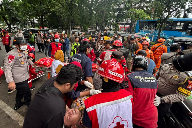 Petugas mengevakuasi polisi yang terluka akibat kebakaran Gedung Terra Drone di Kemayoran, Jakarta Pusat, Selasa (9/12/2025). Foto: Amira Nada Fauziyyah/kumparan