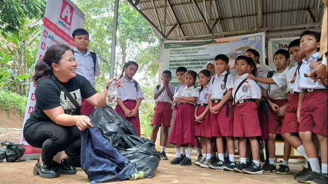 Pengurus Bank Sampah Induk Likupang, Yudith Rondonuwu, saat memberikan penjelasan tentang pemilahan sampah kepada anak-anak SD Negeri Sarawet, Minahasa Utara, dalam program Kampung Merdeka yang digelar oleh Alfamidi Branch Manado.