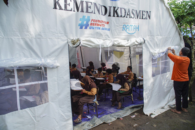 Guru menyiapkan tenda sebelum Asesmen Sumatif Akhir Semester (ASAS) di sekolah darurat bencana erupsi Gunung Semeru di Kecamatan Pronojiwo, Lumajang, Jawa Timur, Sabtu (13/12/2025). Foto: Irfan Sumanjaya/ANTARA FOTO