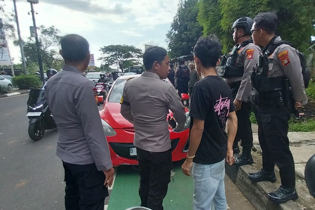 Polisi berjaga di lokasi pemukulan kepada sekelompok orang diduga debt collector di Depok. Foto: Polres Depok