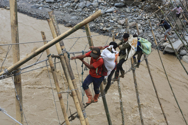 Sejumlah warga korban bencana yang terisolir melintasi Daerah Aliran Sungai (DAS) lewat jembatan tali darurat penghubung dari Desa Bergang Kecamatan Ketol, Aceh Tengah dan Desa Simpang Rahmat, Gajah Putih, Bener Meriah, Aceh, Minggu (14/12/2025). Foto: Syifa Yulinnas/ANTARA FOTO