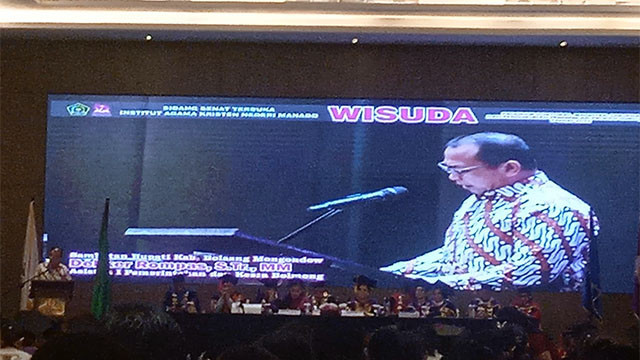 Asisten Pemerintahan dan Kesejahteraan Rakyat Pemkab Bolmong, Deker Rompas, saat membacakan sambutan Bupati Bolmong pada momen Wisuda Gelombang II Tahun 2025, Institut Agama Kristen Negeri (IAKN) Manado.