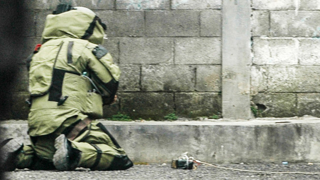 Seorang petugas polisi dari unit penjinak bom memeriksa sebuah benda mencurigakan berbentuk kotak yang dibungkus lakban hitam dengan kabel di depan gereja GKPS di Bandung, Jawa Barat pada 19 Desember 2025. Foto: Timur Matahari / AFP
