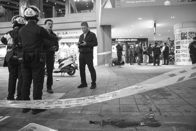 Petugas polisi berdiri di samping bekas darah setelah setelah seseorang melepaskan bom asap dan menyerang pejalan kaki di luar toko Eslite Spectrum Nanxi dekat Stasiun Zhongshan, Taiwan, Jumat (19/12/2025). Foto: Ann Wang/Reuters
