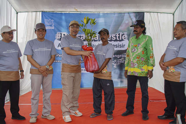 Pada acara #BersamaNestlé: Aksi Nyata Hijaukan Pesisir, serah terima tanaman bakau kepada perwakilan Kelompok Mangrove Dirgahayu Bahari (tengah kanan) oleh Head of Human Resources Nestle Indonesia Pabrik Kejayan Heru Tjahyono. Foto: Dok. Nestlé Indonesia