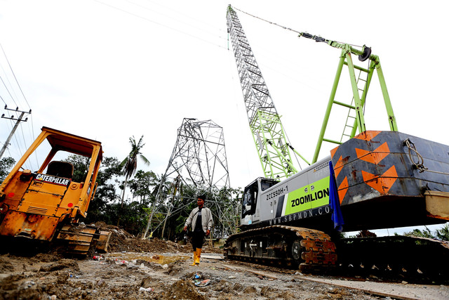 Pekerja melintasi alat berat sejenis crane yang digunakan sebagai tower listrik darurat menggantikan tower yang rusak akibat bencana banjir bandang di Aceh Tamiang, Aceh, Minggu (21/12/2025). Foto: ANTARA FOTO/Irwansyah Putra