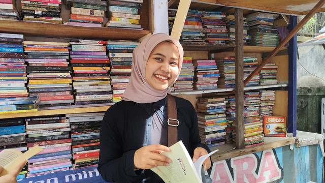 Nensi (20), seorang mahasiswi asal Universitas Islam Sumatera Utara membeli buku di kios buku Satria, Minggu (21/12/2025). Foto: Amar Marpaung/kumparan