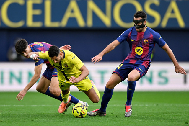 Pemain FC Barcelona Eric Garcia berebut bola dengan pemain Villarreal Ayoze Perez pada pertandingan Liga Spanyol di Estadio de la Ceramica, Villarreal, Spanyol, Minggu (21/12/2025). Foto: Pablo Morano/REUTERS